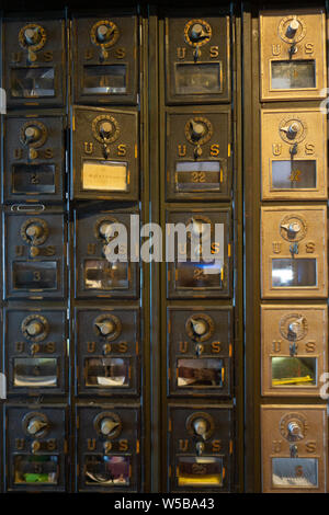 Vista ravvicinata delle cassette postali statunitensi vintage con sportelli in ottone numerati e serrature a combinazione all'interno di un ufficio postale Foto Stock