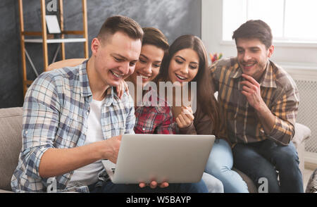 Ridere gli amici a guardare divertenti video su computer portatile Foto Stock