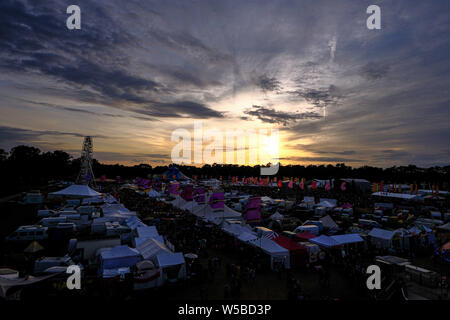 Malmesbury, Wiltshire, Regno Unito. Il 26 luglio 2019. Il sole tramonta oltre il Womad Festival (mondo delle arti di musica e danza) Sabato 27 Luglio 2019 a Charlton Park di Malmesbury. In un giorno di tempo misto, le nuvole consentono il sole a risplendere come set. Foto di Julie Edwards. Foto Stock