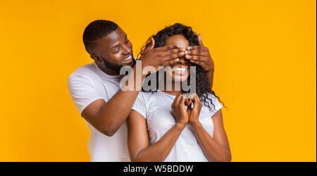 Afro-uomo in piedi dietro la sua donna e chiudendo gli occhi Foto Stock