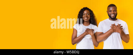 Sorridente afro l uomo e la donna mettendo le mani sui loro cuori Foto Stock