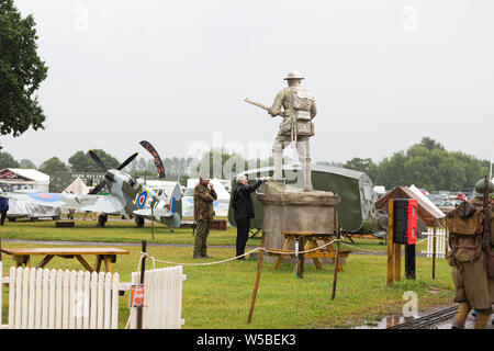 Guerra e Pace Revival 2019, Paddock Wood Hop Farm. Due uomini guardando una statua di un soldato della seconda guerra mondiale. Foto Stock