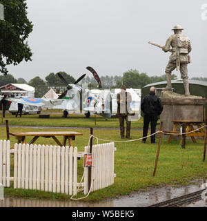 Guerra e Pace Revival 2019, Paddock Wood Hop Farm. Due uomini guardando una statua di un soldato della seconda guerra mondiale. Foto Stock