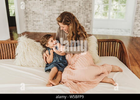 Madre e figlia seduti sul divano solletico e ridere in studio Foto Stock