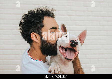Uomo Barbuto baciando un white bull terrier cane Foto Stock