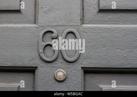 Casa numero 60 con il sessanta dipinto in grigio su un livello di grigio in legno porta anteriore Foto Stock