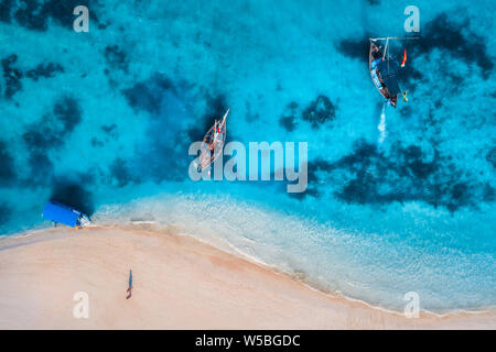 Vista aerea delle barche da pesca in azzurro chiaro acqua al sorgere del sole in estate. Vista dall'alto da fuco di barca, mare blu, spiaggia di sabbia a piedi le persone. Indian Foto Stock