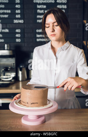 Donna con le mani in mano in camicia bianca crema di levigatura su una parte superiore del cioccolato ca Foto Stock