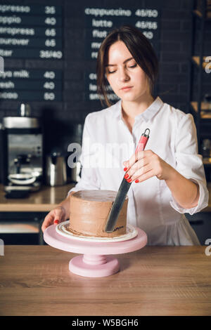 Donna con le mani in mano in camicia bianca crema di smussatura su un lato del cioccolato Foto Stock