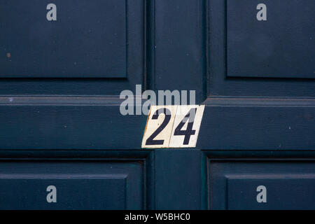 Il numero civico 24 su un blu scuro scolpito in legno porta anteriore Foto Stock