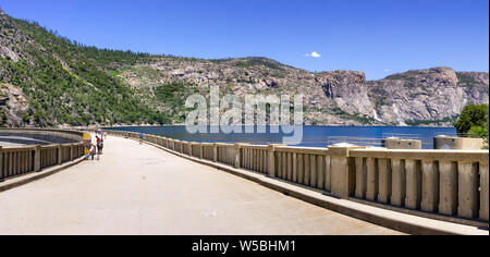 Strada asfaltata sulla sommità di O'Shaughnessy diga; Hetch Hetchy serbatoio visibile sulla destra; il Parco Nazionale di Yosemite; Hetch Hetchy Valley è una fonte di drinki Foto Stock