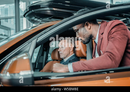 Grave uomo seduto in un auto in salone. Foto Stock