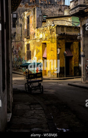 Una bicicletta taxi e carrello vuoto si siede su un angolo di strada in Havana, Cuba Foto Stock