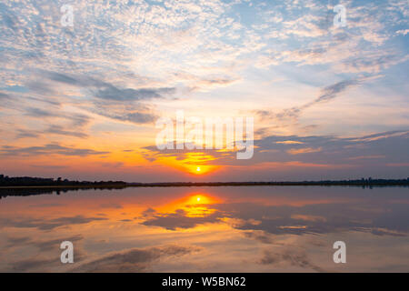 Tramonto riflesso laguna. bel tramonto dietro le nuvole e il blu del cielo sopra la laguna su sfondo paesaggistico. drammatico sky con cloud a sunse Foto Stock