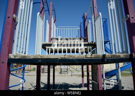 Parco giochi in legno area di arrampicata nel cortile della scuola con la scuola in background. Foto Stock