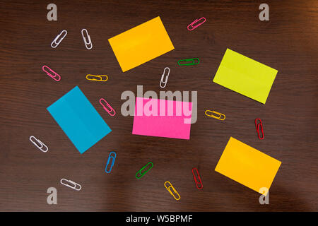 Colorato sticky notes e schizzi di fermagli per carta marrone sulla scrivania in legno. Vista superiore e spazio per il testo. Close up, il fuoco selettivo Foto Stock