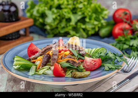 Succosa carne di manzo Lombata di manzo con insalata di pomodori arrosto, il formaggio feta e verdure verdi in una piastra blu. cibo sano Foto Stock