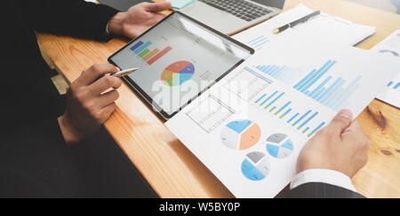 Un gruppo di persone di affari per discutere il piano di statistiche con grafici e tabelle Foto Stock