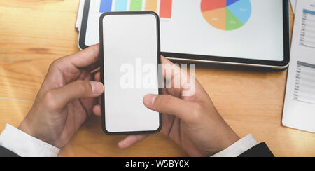 Imprenditore il mano azienda schermo vuoto smartphone in sala riunioni mentre esprimono le idee con i grafici Foto Stock