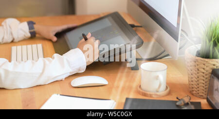 Libero professionista retoucher donna funziona su computer desktop con editing di foto tablet in studio di office Foto Stock