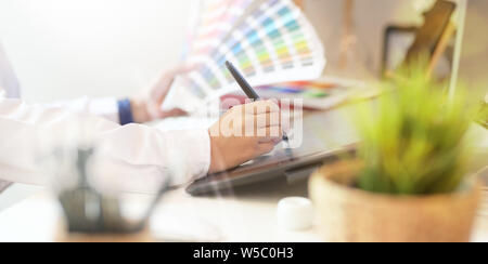 Libero professionista retoucher donna funziona su computer desktop con editing di foto tablet in studio di office Foto Stock