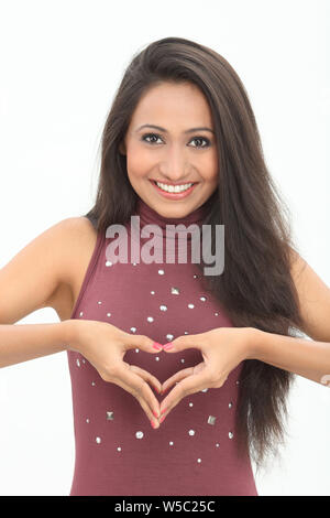 Donna messa a forma di cuore con le sue mani e sorridente Foto Stock