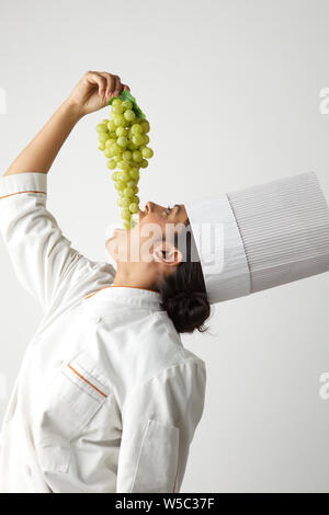 Lo Chef mangiare grappolo di uva Foto Stock