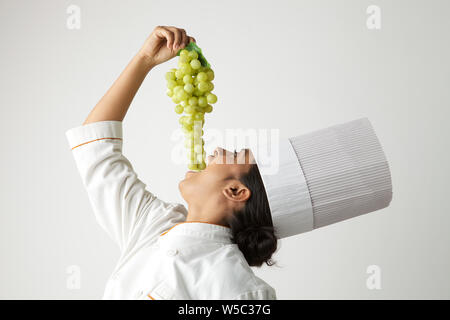 Chef indiano mangiare grappolo di uva Foto Stock