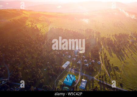 Panorama delle montagne con piccolo villaggio in Altai su un estate giorno chiaro. Una vista panoramica della splendida fresco verde campo e Altai mountain ba Foto Stock