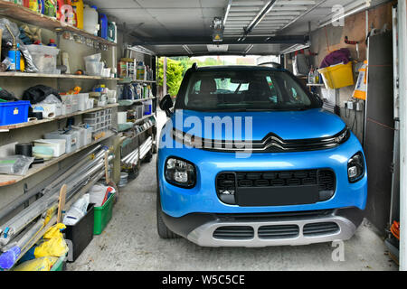 Auto Citroen Aircross parcheggiata accanto a casa proprietà residenziale scaffalature garage per deposito varie paraphernalia e utensili per la casa Inghilterra Regno Unito Foto Stock