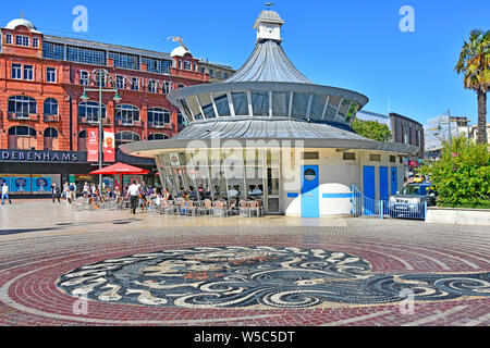 Centro di Bournemouth la piazza e mosaico di ciottoli nella pavimentazione con negozio Debenhams & persone seduti all'aperto a Obscura street cafe Dorset England Regno Unito Foto Stock