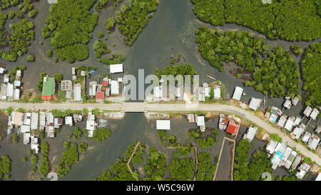 Autostrada attraverso la foresta di mangrovie passando attraverso il villaggio, vista aerea. Siargao island, Filippine. Foto Stock