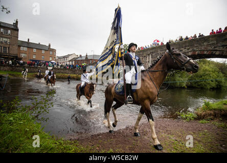 L onesto Lad Aidan Maguire conduce la cavalcata del cavallo di piloti che partecipano nel maneggio delle Marche attraverso il fiume Esk a fianco del ponte romano a Musselburgh, East Lothian, durante l'annuale Festival di Musselburgh organizzato dall onesto Toun l'Associazione. Foto Stock