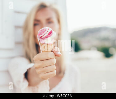 Giovane donna europea detiene il fuso gelato alla fragola di fronte a lei Foto Stock