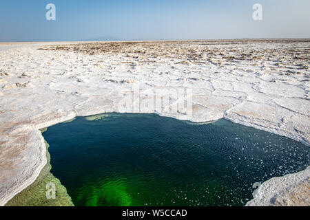 Acqua di lago Karum, visibile attraverso un foro nella distesa di sale, Danakil depressione, Etiopia. Foto Stock