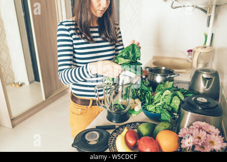 La ragazza in abbigliamento casual in cucina prepara prodotti freschi verdi per un frullato Foto Stock