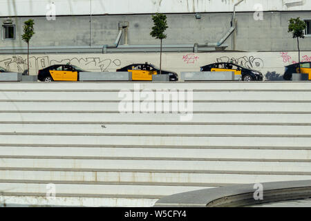 Nero e Giallo taxicabs schierate a Barcellona al di sopra di una scalinata e di fronte a un graffiti'ed parete. Include lo spazio per la copia in basso Foto Stock