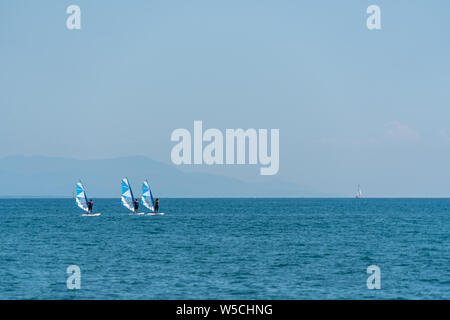 Tre wind surf nuotare fianco a fianco sul mare Foto Stock