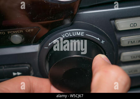 Una persona ruotando la rotellina del volume in alto o in basso (il focus è sulla parola 'volume' scritta sul dispositivo) Foto Stock