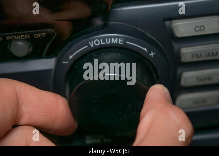 Una persona ruotando la rotellina del volume in alto o in basso (il focus è sulla parola 'volume' scritta sul dispositivo) Foto Stock