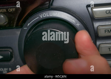 Una persona ruotando la rotellina del volume in alto o in basso (il focus è sulla parola 'volume' scritta sul dispositivo) Foto Stock