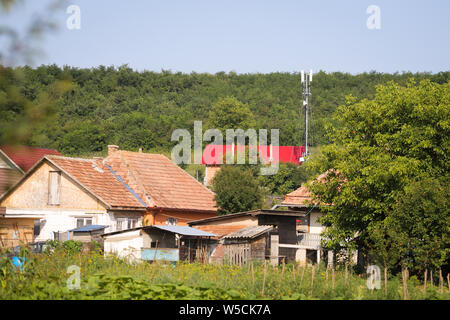 4G e 5G antenne in un villaggio, tra case e vegetazione pesante in Romania rurale Foto Stock