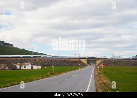 AVE il treno ad alta velocità che viaggiano lungo un ponte su una strada. Fuente El Fresno, Ciudad Real Provincia, Castilla La Mancha, in Spagna. Foto Stock