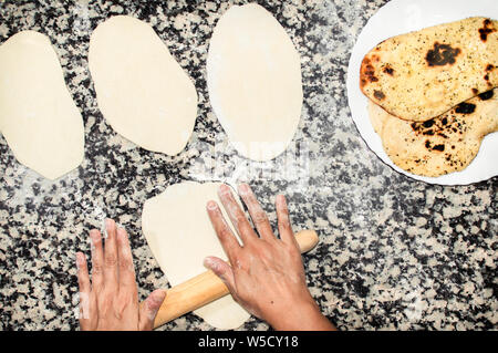 Lo chef preparare in casa pane Naan indiano Asian o pane. Processo di preparazione, impastare la pasta sul tavolo di cucina e delizioso pane pronto a mangiare. Foto Stock