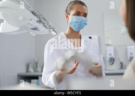 Ritratto di giovane donna dentista di indossare la maschera protettiva consulting paziente in clinica, spazio copia Foto Stock
