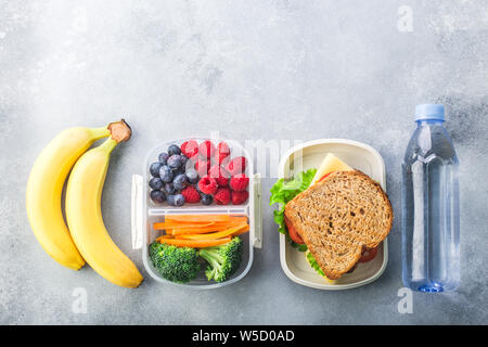 Scuola scatola di pranzo a sandwich con verdure acqua di mandorle e frutta sulla tabella grigia sano Foto Stock