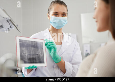 Ritratto di giovane donna dentista che mostra denti immagine a raggi x al paziente durante la consultazione in clinica, spazio copia Foto Stock