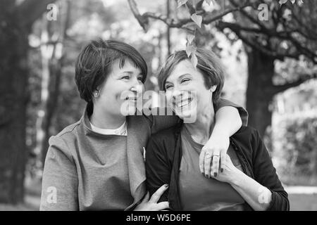 Felici donne cuddling, passeggiate nel parco e in appoggio, lifestyle ritratto in bianco e nero Foto Stock