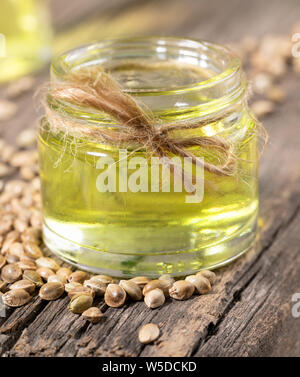 Olio di canapa in un barattolo di vetro e grani di cannabis su sfondo di vecchio di tavole di legno di close-up. Foto Stock