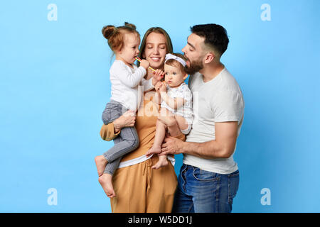 La famiglia felice di mangiare lecca-lecca mentre in piedi su sfondo blu. studio shot. close up verticale. La felicità, l'amore,forte rapporto Foto Stock